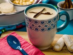 a cup of coffee sitting on top of a wooden table next to bowls of food