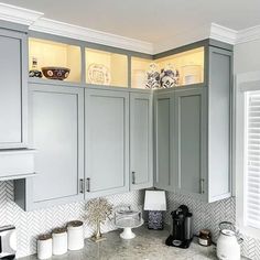 a kitchen with gray cabinets and marble counter tops, along with white trim on the walls