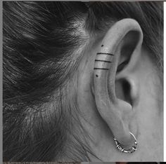 a woman's ear with two piercings on it and the word love behind her ear