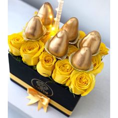 a box filled with yellow roses and chocolate covered heart shaped candies next to a lit candle