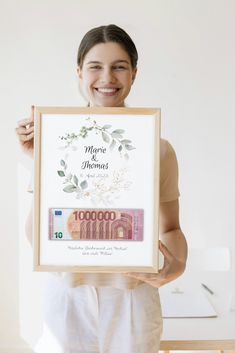 a woman holding up a framed photo with money