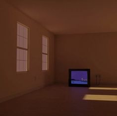 an empty room with two windows and a television on the floor in front of it