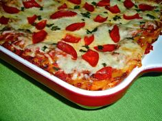 a pizza with cheese and pepperoni on it sitting in a red casserole dish