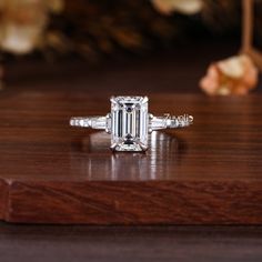 an emerald cut diamond ring on a wooden table