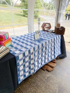 a blue and white checkered table cloth on top of a wooden pallet under a tent