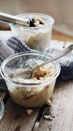 two bowls filled with oatmeal sitting on top of a wooden table next to spoons