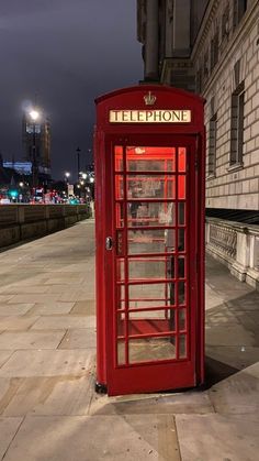 a red phone booth sitting on the side of a street