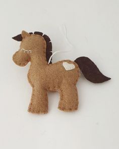 a brown felt horse ornament hanging on a white wall next to a string