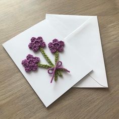 two crocheted flowers sitting on top of an envelope