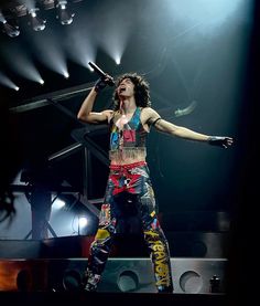 the woman is singing on stage with her arms out and hands in the air as she holds