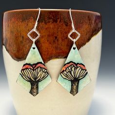 "These one of a kind earrings feature detailed paintings of mushrooms working from my own photo of mushrooms I found on a hike. These light, wood earrings are hand-painted with acrylic paint and liquid pearlescent acrylic inks, then sealed with liquid glass. The edges of the earrings are painted with gold paint. I hand formed the earring hooks and jump rings from 20 gauge half hard sterling silver wire.  Earrings (painted wood) each approximately 1 & 5/8\" long, 1 & 1/8\" in widest part Earrings with attached earring wires each approximately 2.75\" long **Listing is for earrings only and does not include any props or pottery as seen in the photos. Your earrings will arrive ready for gifting in a gift box inside the package." Unique Mushroom Design Earrings For Gift, Unique Mushroom Design Earrings As Gift, Nickel-free Mushroom-shaped Earrings For Gifts, Nickel-free Mushroom Shaped Earrings As Gift, Whimsical Mushroom Print Jewelry Gift, Mushroom Earrings, Detailed Paintings, Earring Wires, Made Jewelry