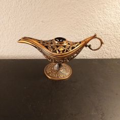 an ornate gold and black vase sitting on top of a table