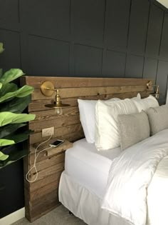 a bed with white linens and pillows in a room next to a green plant