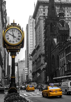 a black and white photo of a clock in the middle of a busy city street