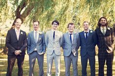 a group of men standing next to each other in front of a large willow tree