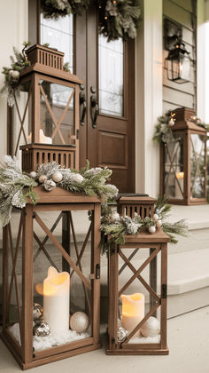 two wooden lanterns with lit candles on the front steps and wreaths hanging from them