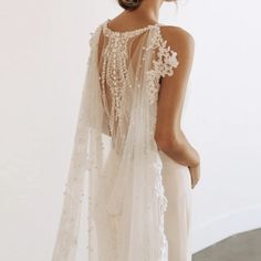 the back of a woman's wedding dress with sheer, beaded sleeves and veil