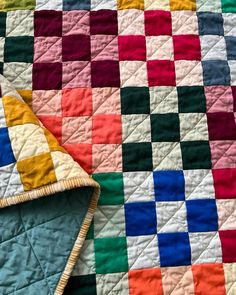 two quilts are laying next to each other on a bed with colorful squares in them