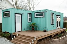 a tiny house made out of shipping containers with steps leading up to the front door