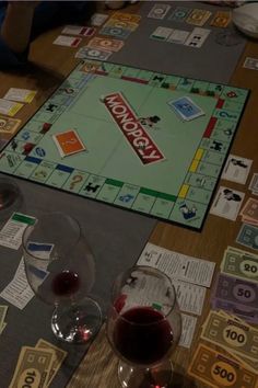 a monopoly board game on a table with wine glasses