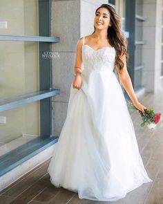 a woman in a white wedding dress is walking down the street with her hand on her hip