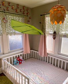 a baby's crib with a green umbrella hanging from the ceiling