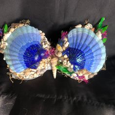 two blue shells with green leaves and seashells on them