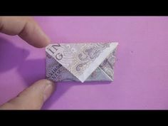 an origami envelope made out of money sitting on top of a purple surface