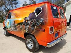 an orange van with bicycles painted on it's side is parked in front of a house