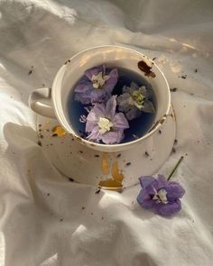 a cup filled with water and purple flowers