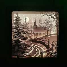 a paper cut scene with a church and trees in the snow at night, on a green background