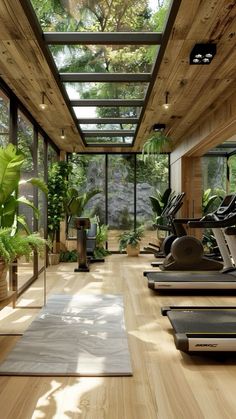 there are many exercise machines in this room with wood flooring and glass walls on the ceiling