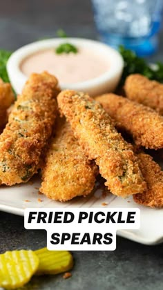 fried pickle spears on a plate with dipping sauce