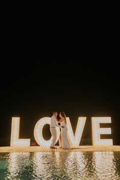 a bride and groom standing in front of the word love