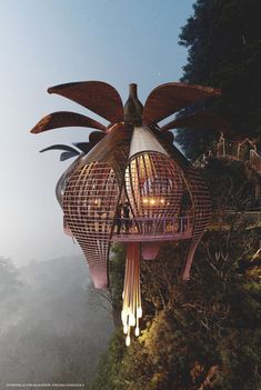 a bird shaped building with lights hanging from it's wings on top of a cliff