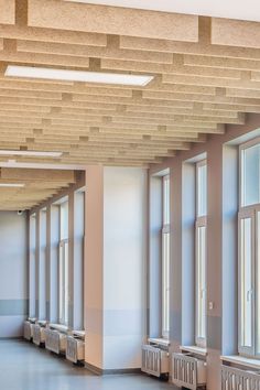 an empty room with several windows and radiators on the ceiling, in front of two rows of benches