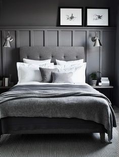 a bedroom with gray walls and white bedding, two framed pictures on the wall