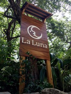 the sign for la lunaa is in front of some trees and rocks with leaves around it