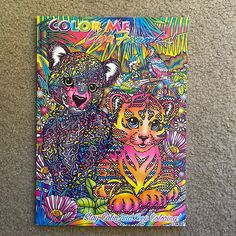 an adult coloring book with two cats on the cover and flowers in the background, sitting on a carpeted floor