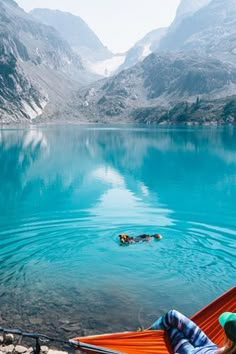 a person laying in a hammock on the edge of a lake