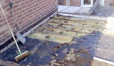 a broom is laying on the ground in front of a brick building with steps leading up to it