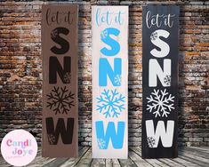 three snowboards are standing next to each other on a brick wall with the words let it snow, let it snow and let it snow