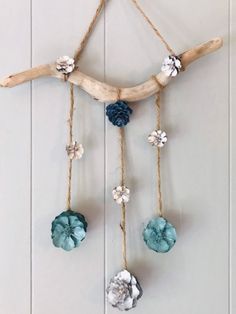 a piece of driftwood with flowers hanging from it's sides on a wall