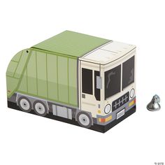 a paper model of a green garbage truck next to a silver bell on a white background