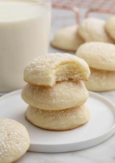 several sugar cookies stacked on top of each other with a glass of milk in the background