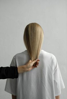 a woman with blonde hair is straightening her long hair