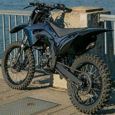 a dirt bike parked next to a railing near the water