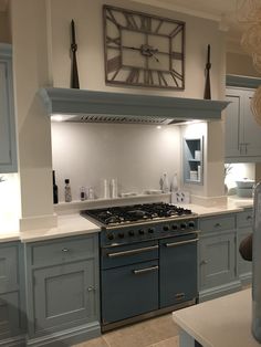 a kitchen with blue cabinets and a clock on the wall above the stove top oven