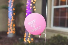 a pink balloon with the words boy and girl on it hanging from a pole in front of a house