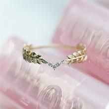 a gold ring with leaves on it sitting on top of a pink plastic container next to a pair of glasses